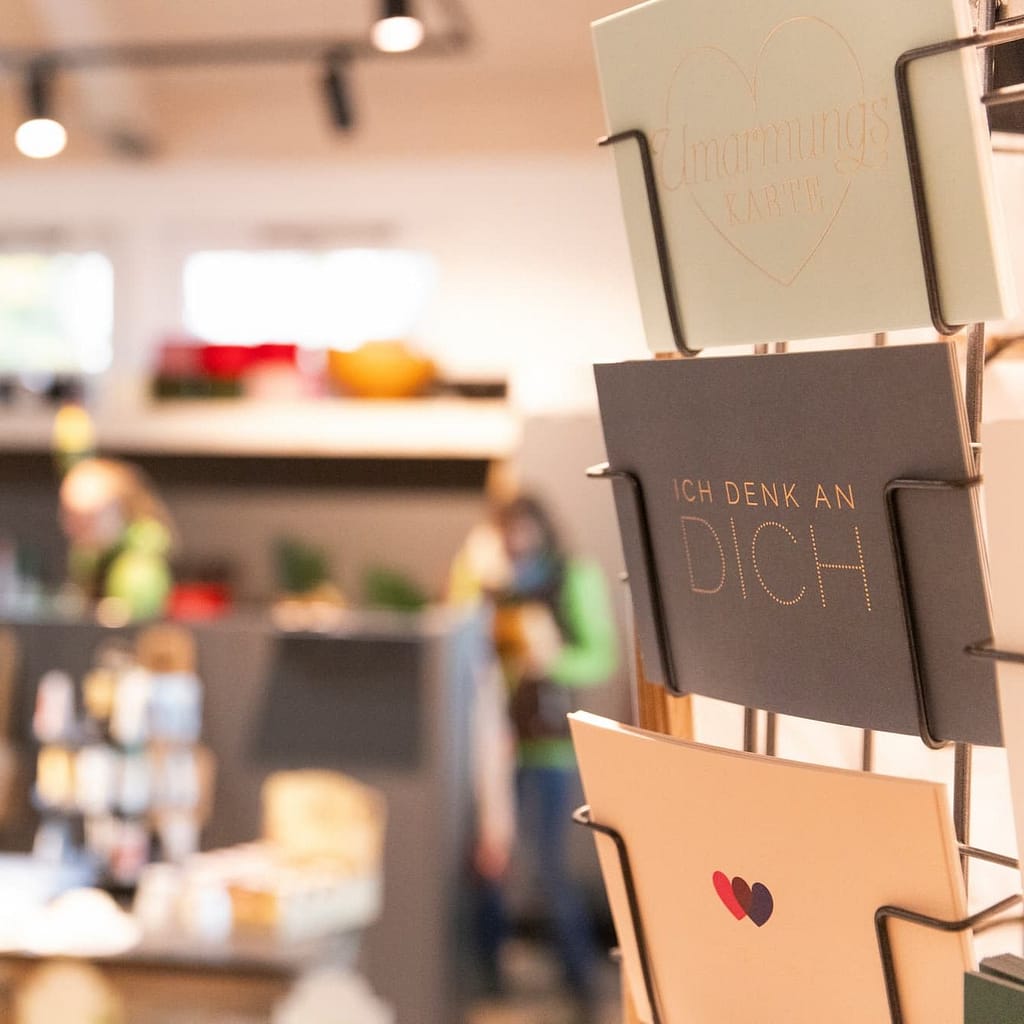 Grußkarten-Ständer mit Karten wie "Ich denk an dich" im Blumenladen Heck