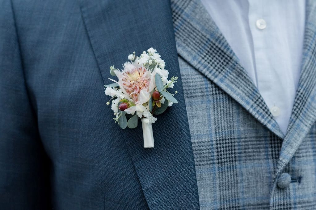 Anstecker mit Rosen und Hypericum-Beeren an dunkelblauem Anzug