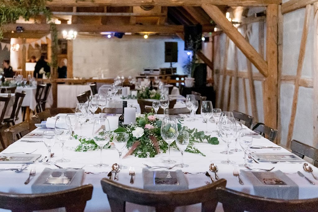Rustikal gedeckter Tisch mit Blumenschmuck in Scheune mit Holzbalken