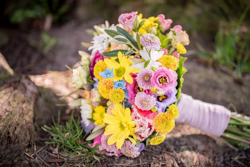 Bunter Brautstrauß in Gelb, Pink und Weiß auf Waldboden