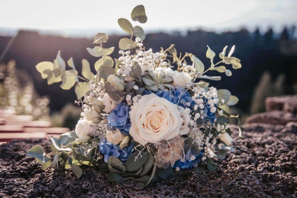 Blau-weißer Brautstrauß mit Rosen und Hortensien auf Stein