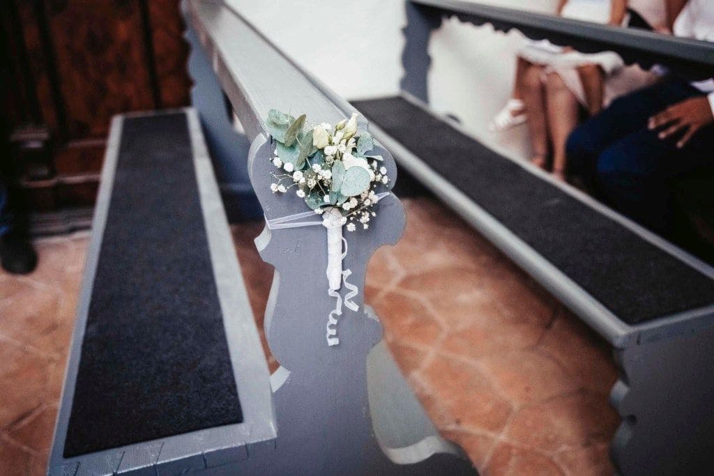 Schleierkraut-Blumenschmuck an Kirchenbank, Gäste im Hintergrund