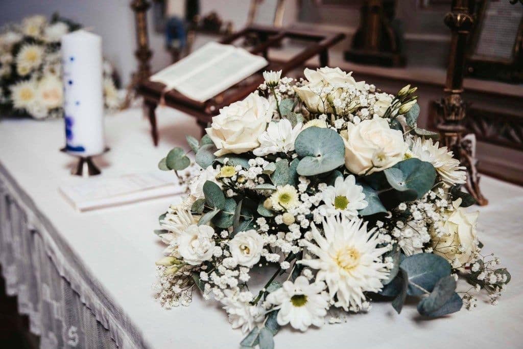 Weißer Brautstrauß auf Altar mit Kerze und Gebetbuch