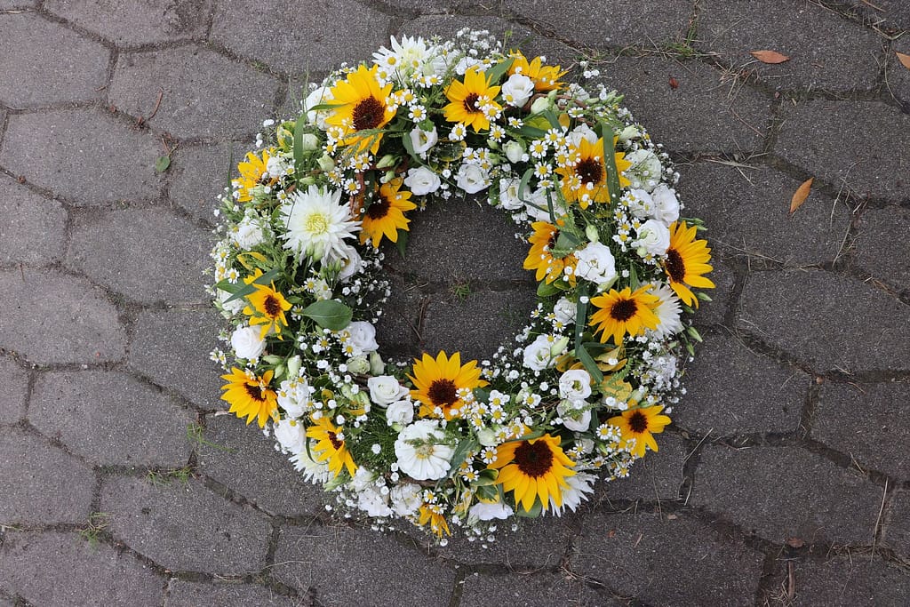 Urne mit Sonnenblumenschmuck auf Kerzenständer in der Kirche