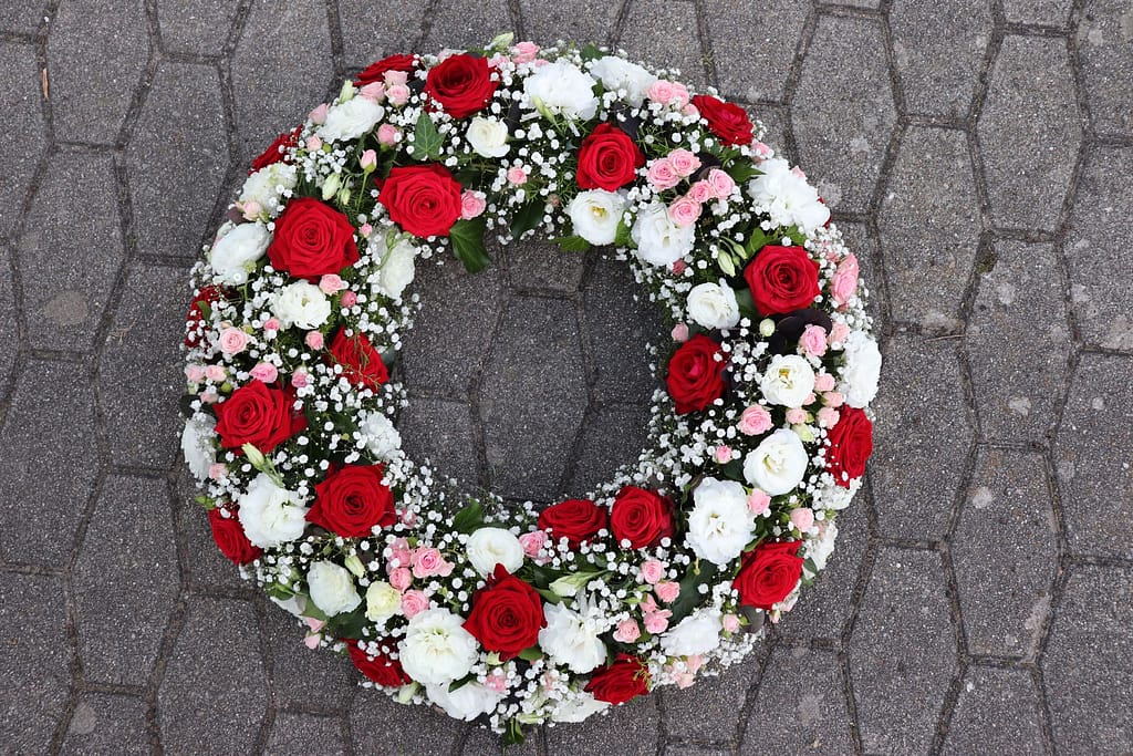 Roter Trauerkranz mit weißen und rosa Rosen