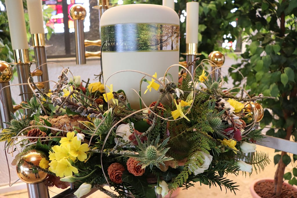 Urne mit Frühlingsblumenschmuck aus Narzissen und Disteln