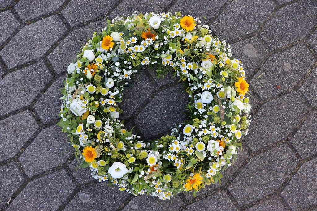 Weiß-gelber Trauerkranz mit Margeriten und Sonnenblumen