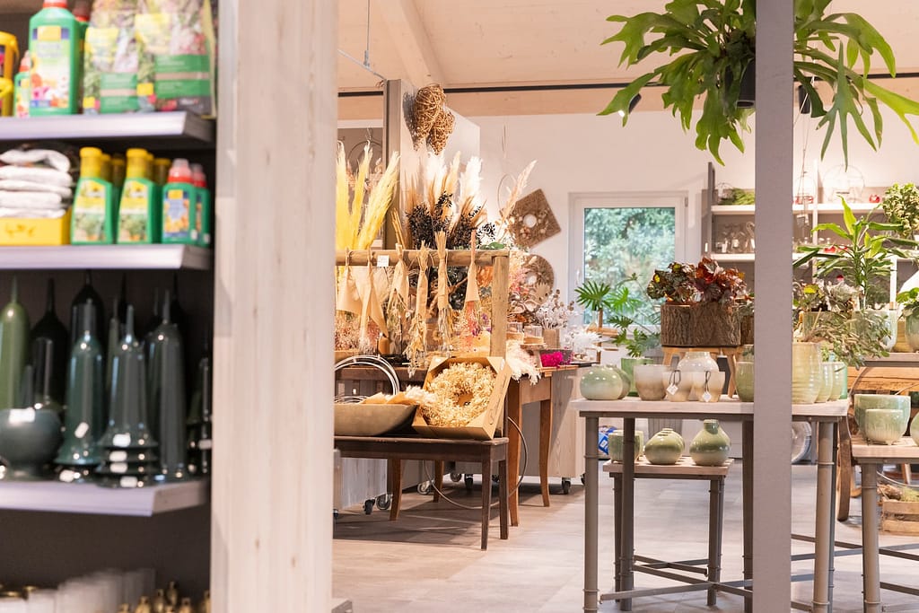 Regal mit Dünger und Pflanzenpflege-Produkten neben Trockenblumen-Arrangements