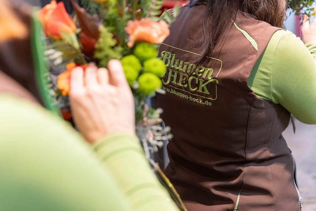 Bestickte Arbeitsschürze mit dem Logo von Blumen Heck bei der Straußbindung