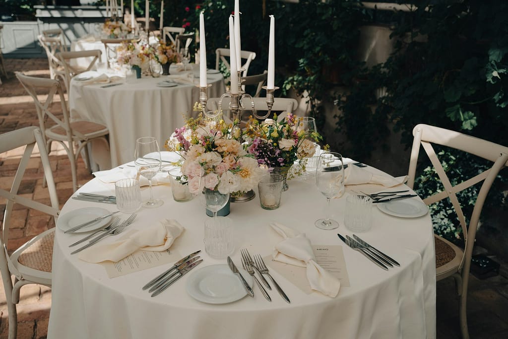 Runder Hochzeitstisch mit Tischtuch, Blumen und Stabkerzen