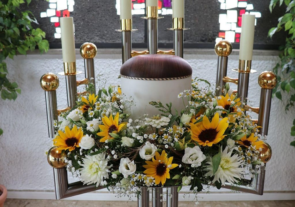 Urne mit Urnenkranz aus Sonnenblumen auf einem Kerzenständer in der Kirche