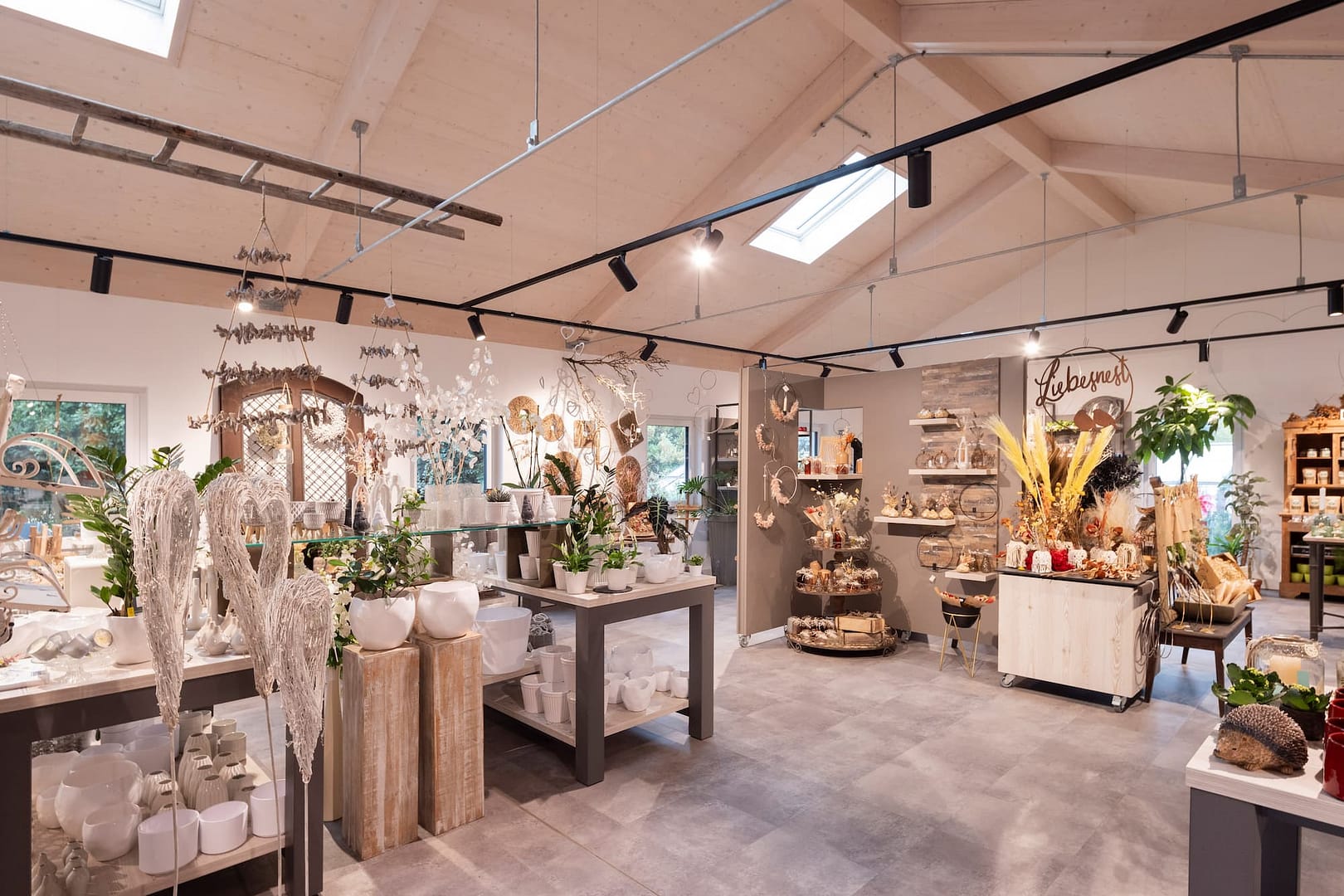 Deko-Ecke "Liebesnest" mit weißen Flügel-Ornamenten und Keramikvasen im Blumenladen Heck
