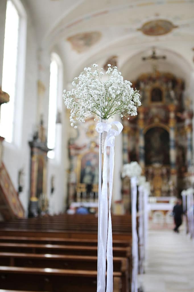 Schleierkraut-Blumenschmuck an Kirchenbank mit weißen Bändern