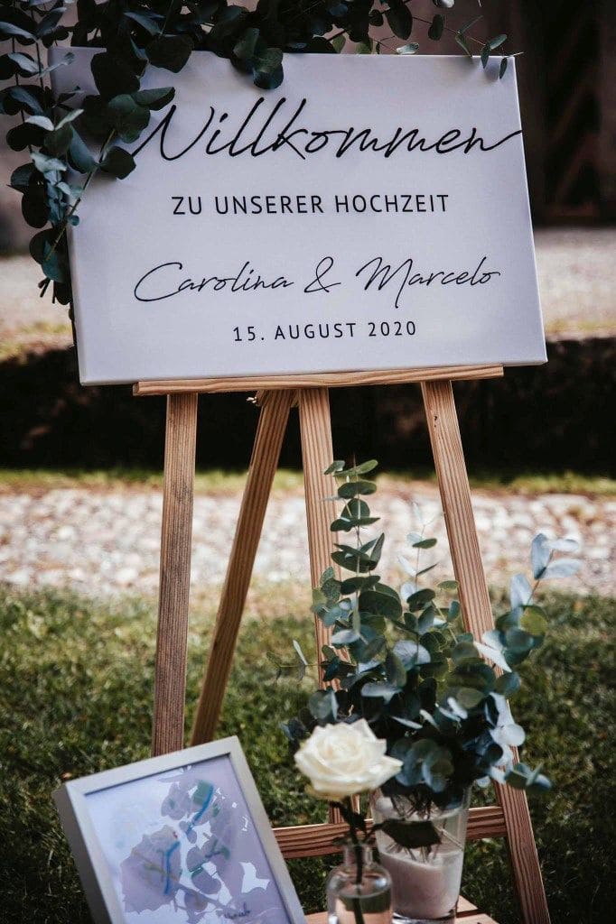 Willkommensschild "Carolina & Marcelo" mit Eukalyptus-Dekoration im Garten