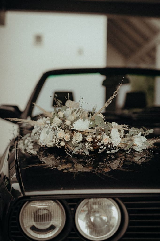 Blumenschmuck aus Trockenblumen auf Motorhaube eines Hochzeitsautos
