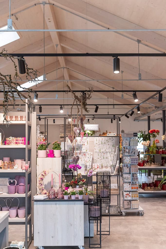 Geschenkregal zum Valentinstag mit rosa Töpfen, Orchideen und Grußkarten