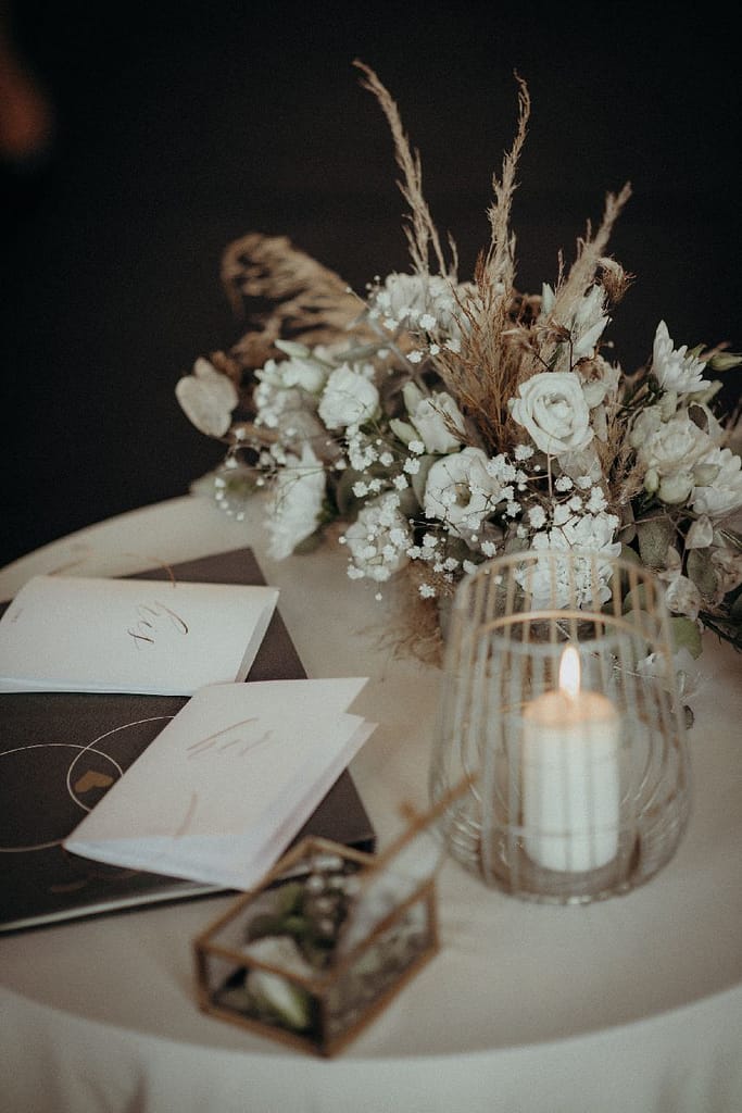 Tischdekoration mit Trockenblumen, Kerze und Hochzeitskarten