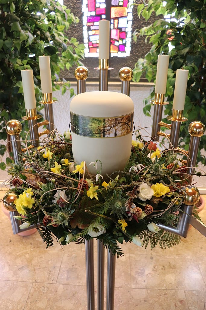 Urne mit gelbem Frühlingsblumenschmuck auf Kerzenständer in der Kirche