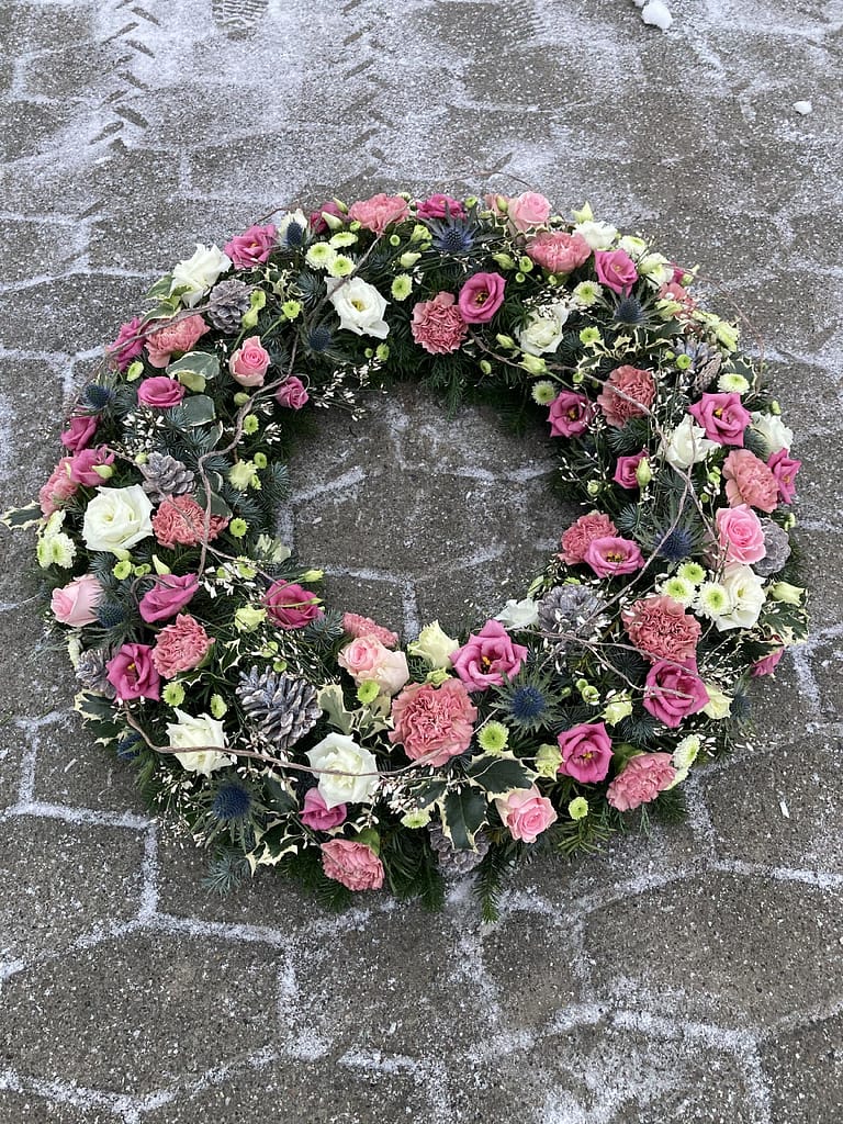 Rosa-weißer winterlicher Trauerkranz mit Tannenzapfen im Schnee