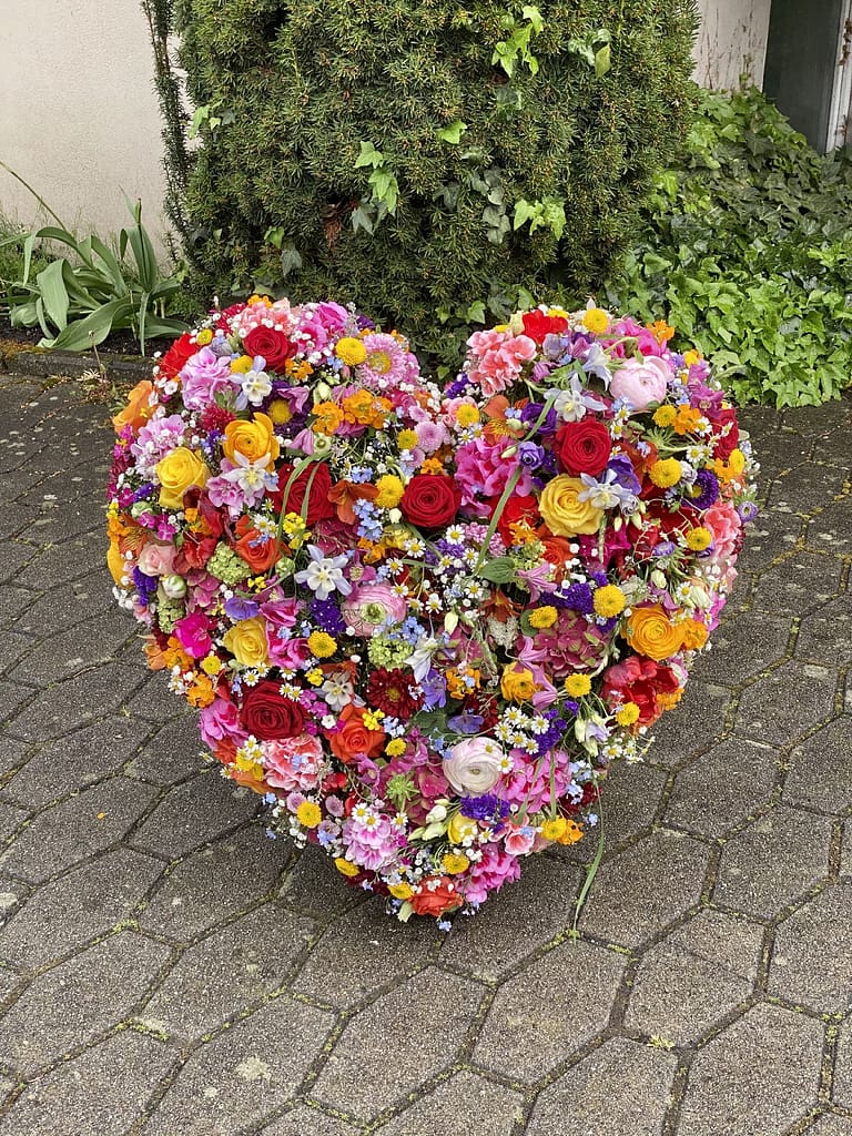 Buntes Herzgesteck mit Rosen und Ranunkeln