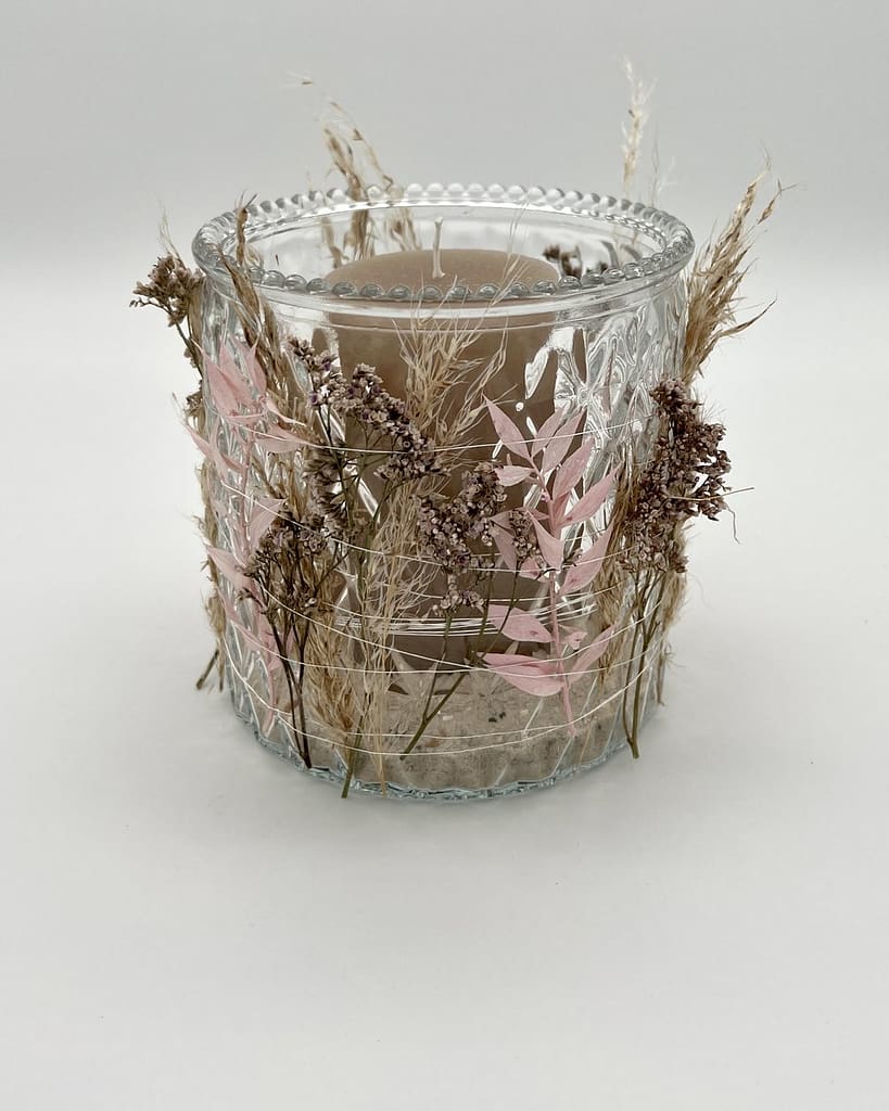 Windlicht aus Glas mit Trockenblumen und Gräsern